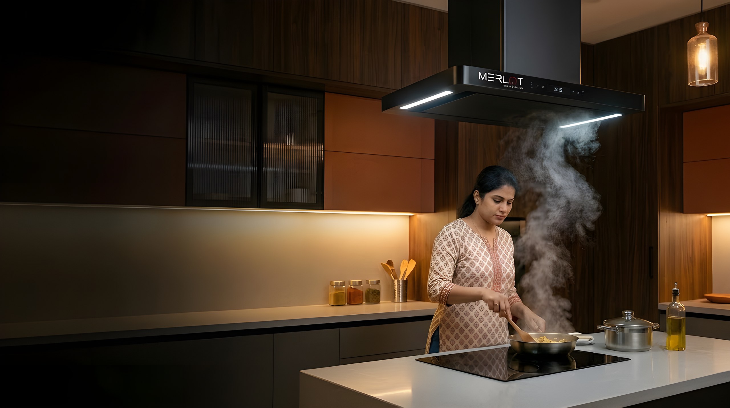 Woman cooking on an island hob beneath a Merlot Isle ceiling-mounted chimney, steam drawing up into the hood